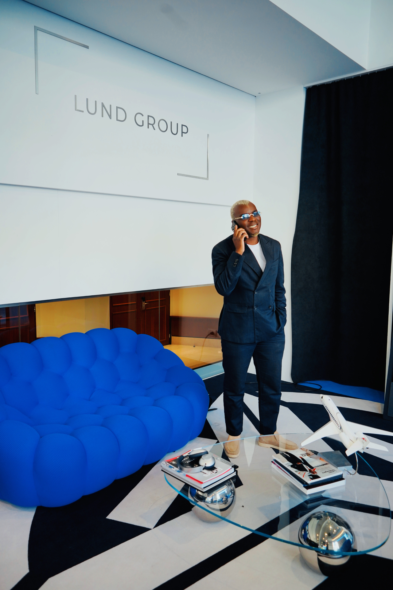 Lucien Ndabagera on the phone in the LUND GROUP interior with a blue sofa and model aircraft